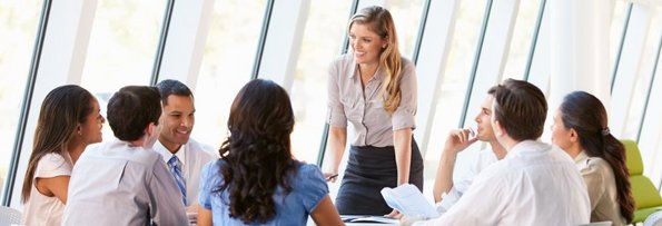 Eine Frau leitet ein Meeting mit einer Gruppe aus mehreren Personen